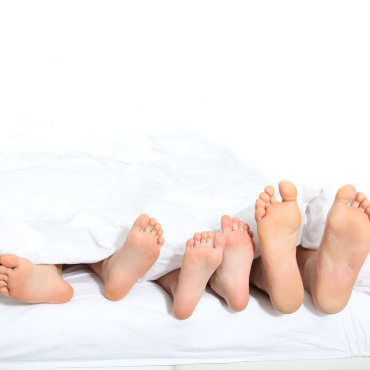 Pieds d'une famille couchée dans un lit blanc