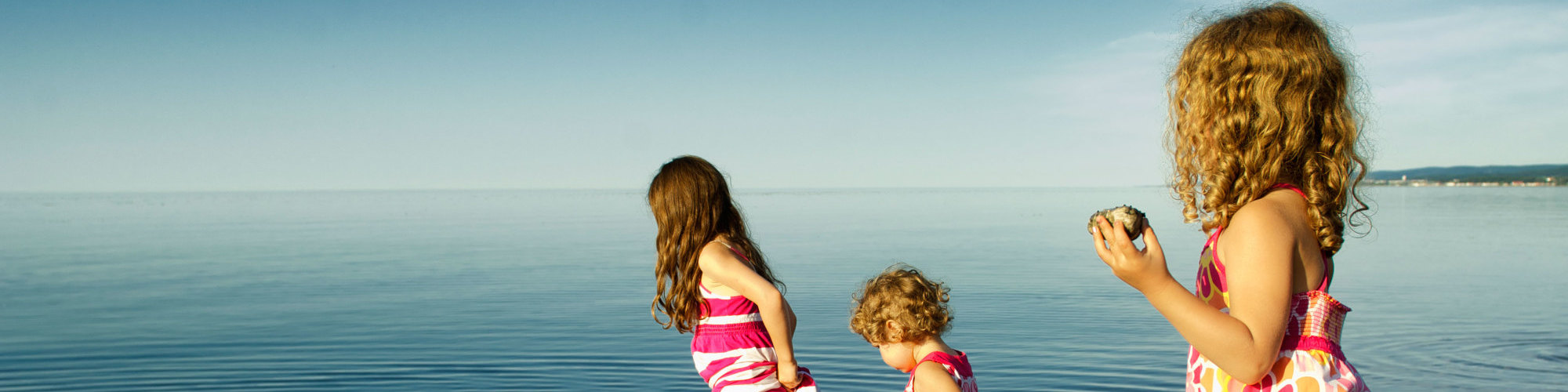 3 petites filles qui jouent dans l'eau, sur la plage