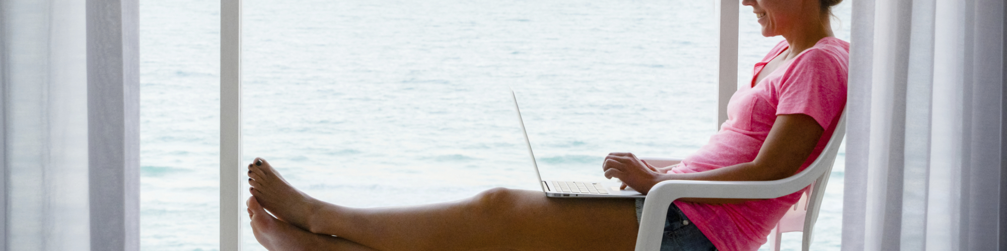 Femme assis sur une terrasse, bord de mer, avec un ordinateur portable