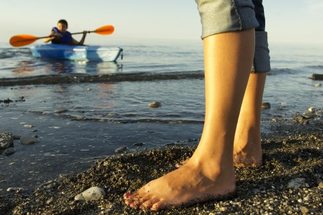 Bare feet on the beach, young boy sea kayaking